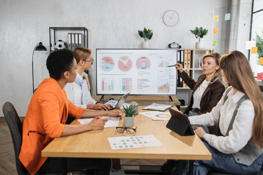 Four female partners sitting at desk and discussing common project.